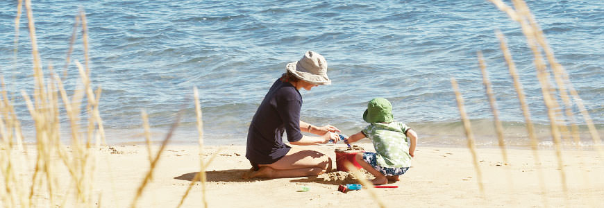 Mor og barn leker på stranden